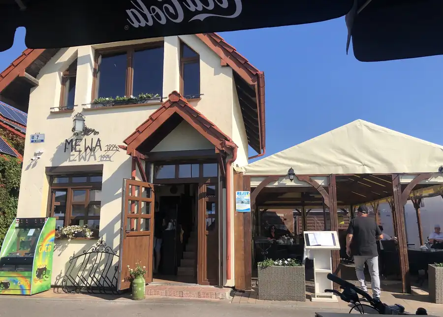 Biały budynek restauracji Mewa z napisem nad wejściem
