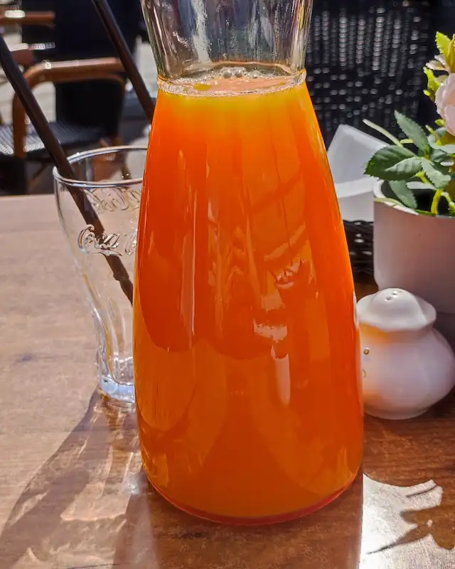 Dzbanek pomarańczowego soku na stoliku w ogródku