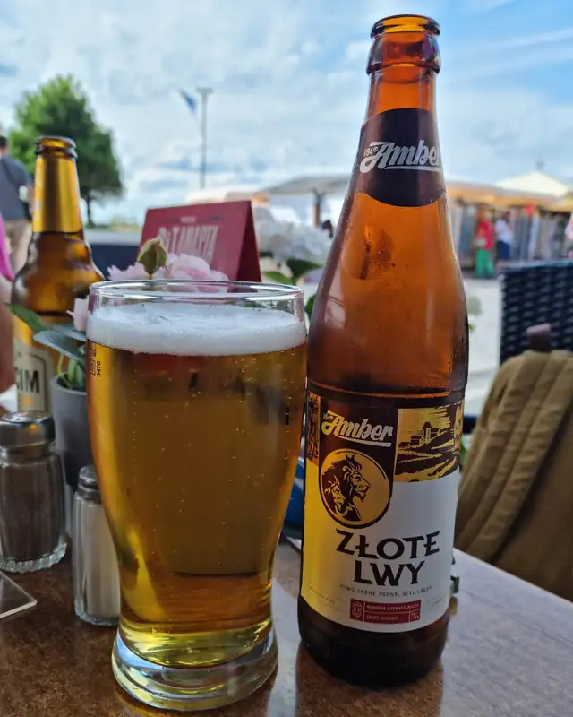 Piwo Złote Lwy w szklance na stoliku